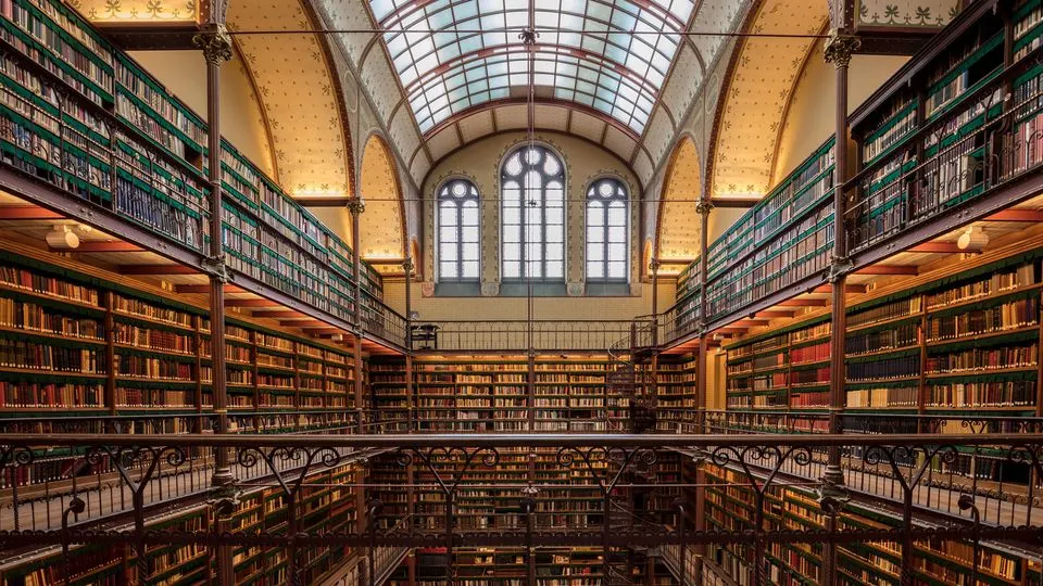 Les rayonnages sur trois niveaux d’une grande bibliothèque, éclairés par une verrière
